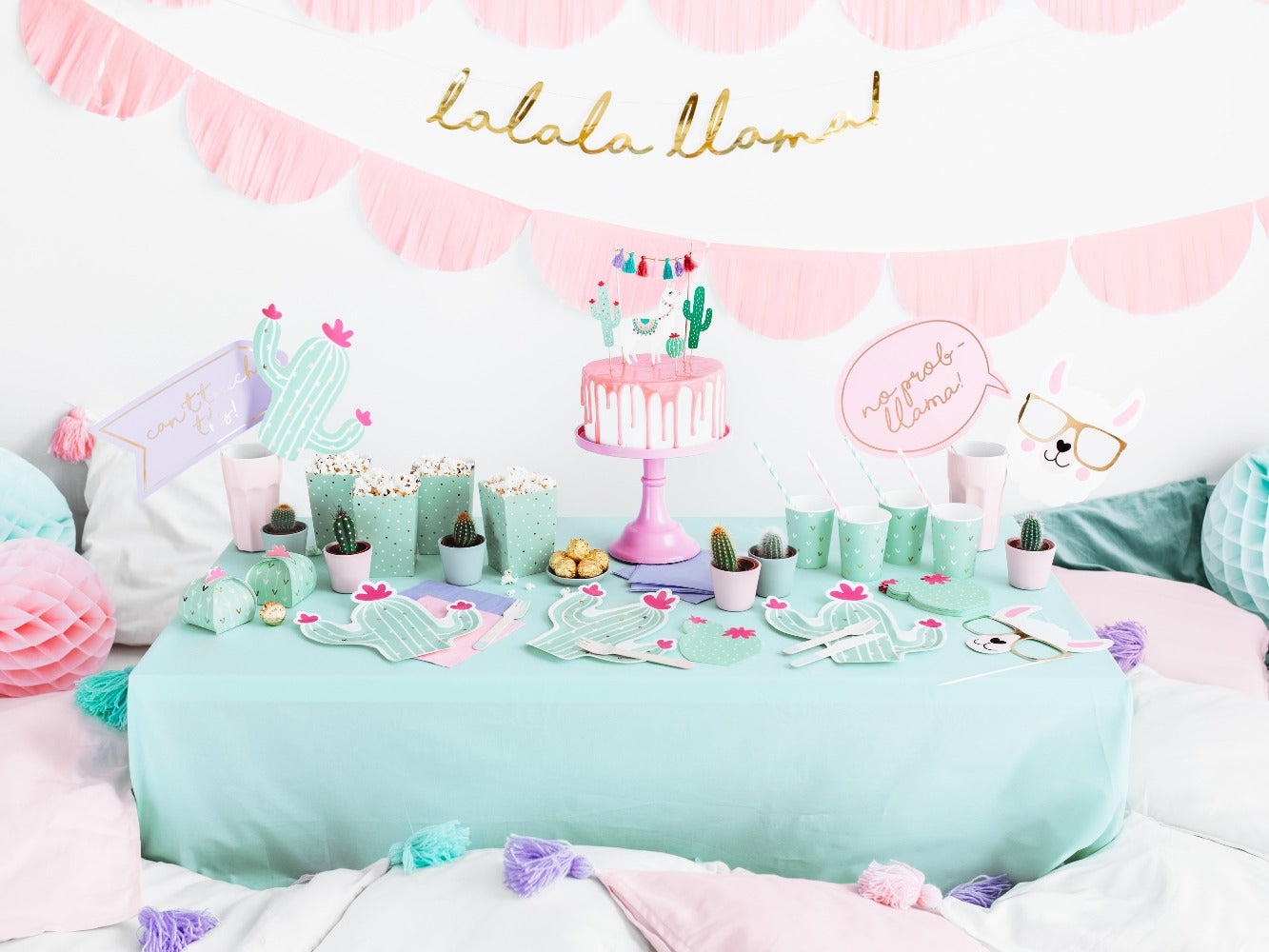 Boho Llama party decorations with gold llama garland, mint party cups with gold details, mint coloured cactus shaped plate with hot pink details, straws and napkins.
