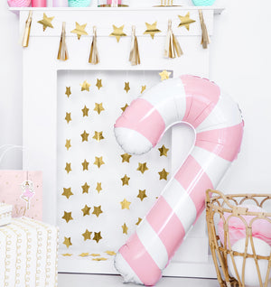 Christmas and new years party decorations with candy cane helium balloon, nutcracker garland and stars. In pink and gold.