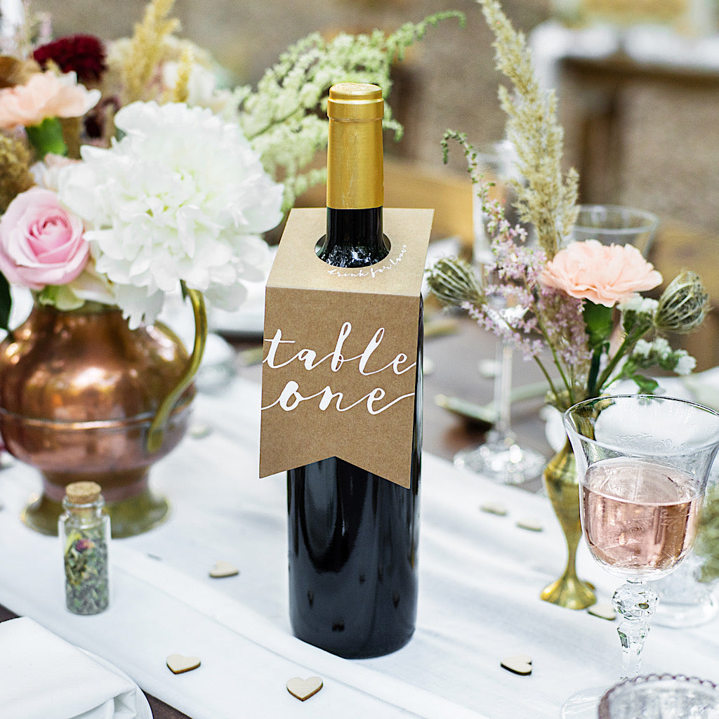 wedding bottle hanger table numbers in brown kraft paper with white descriptive writing
