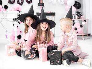 children celebrating halloween with witches hats and black and pink party bags. 